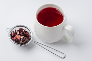 red hibiscus tea in a white mug and dry blossom isolated on white background, selective focus