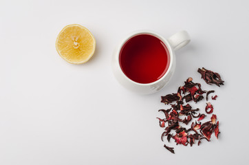 Obraz na płótnie Canvas red hibiscus tea in a white mug, lemon segment and dry blossom isolated on white background. Top view and copyspace