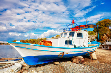Traditional Turkish fishing boat ashore for maintenance on Gumusluk bay in Bodrum, Turkey.