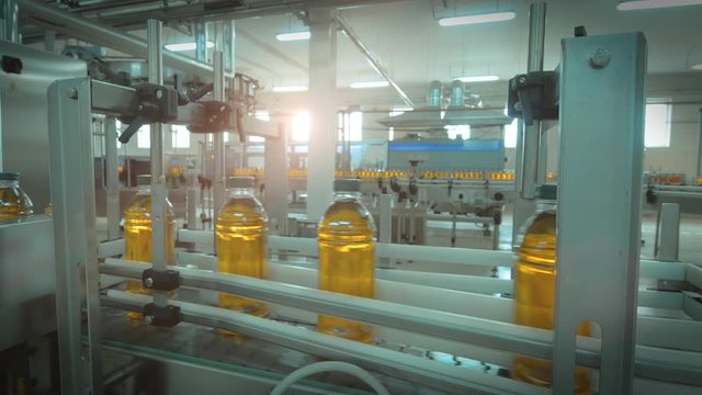 Conveyor belt production line of juice on beverage plant or factory, modern industrial equipment. Fresh juice in PET plastic bottles