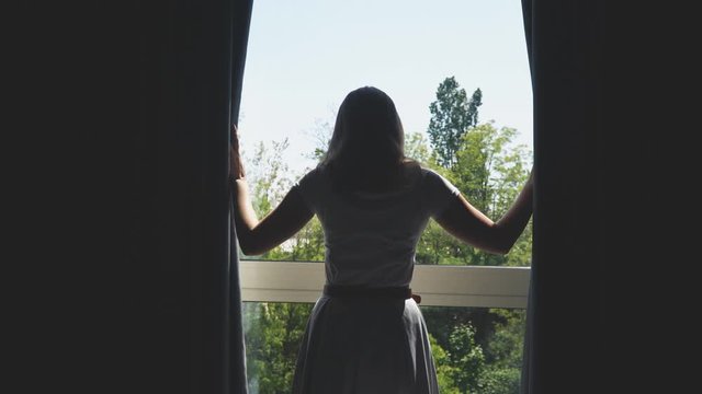 Woman opening curtains in the hotel room.