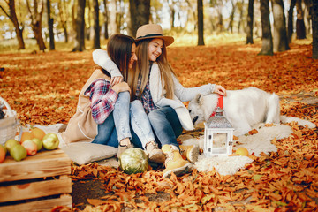 Fototapeta premium Beautiful girls in a park. Cute ladies in a stylish clothes. Friends with cute dog