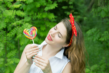 girl with a lollipop in the trees in the summer day