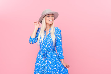Portrait of a smiling attractive blond woman in summer hat and stylish blue dress and in braces...
