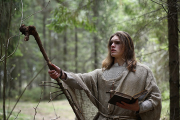 A man in a cassock spends a ritual in a dark forest