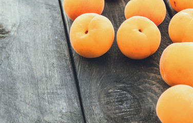 Ripe yellow apricots lie on a wooden table.