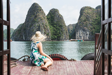 Caucasian blonde woman in a straw hat enjoying the boat ride at Lan Ha Bay, Cat Ba island, Vietnam