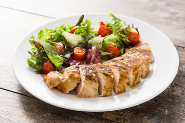 Grilled chicken breast with vegetables on a plate on wooden table