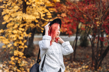 Pretty girl with red hair and hat walking in the park, autumn time.