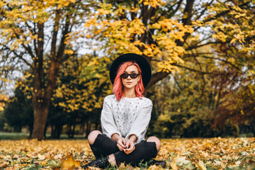 Pretty girl with red hair and hat relaxing in the park, autumn time.