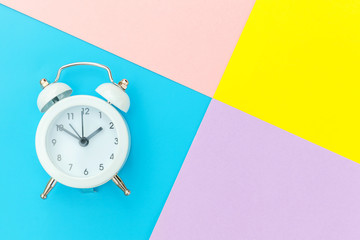 Ringing twin bell classic alarm clock isolated on blue yellow pink pastel colorful geometric background. Rest hours time of life good morning night wake up awake concept. Flat lay top view copy space