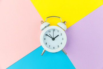 Ringing twin bell classic alarm clock isolated on blue yellow pink pastel colorful geometric...