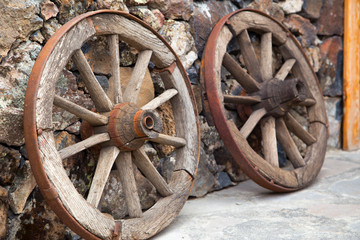 Two wheels from the cart stand against the wall. Horizontally.