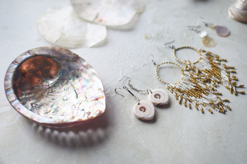 Sea collection on grey marble background.Seashell and mother-of-pearl earrings. Summer jewelry.