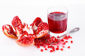 Pomegranate fruit with seeds on a white background. A glass of pomegranate juice