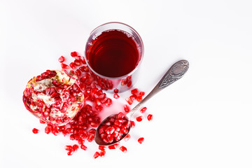 Pomegranate fruit with seeds on a white background. A glass of pomegranate juice