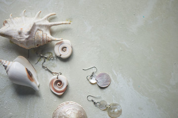 Sea collection on grey marble background.Seashell and mother-of-pearl earrings. Summer jewelry.