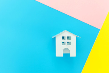 Simply design with miniature white toy house isolated on blue yellow pink pastel colorful trendy geometric background Mortgage property insurance dream home concept. Flat lay top view copy space