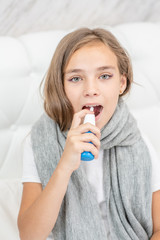 Young girl spraying in her mouth with a spray from the pain in her throat
