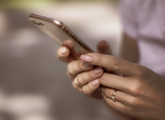 Beautiful woman hands holding mobile phone. Closeup. Soft sunlight. Blur background. Beautiful manicure
