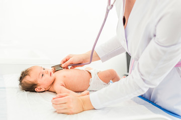 Pediatrician doctor examines baby girl with stethoscope checking heart beat