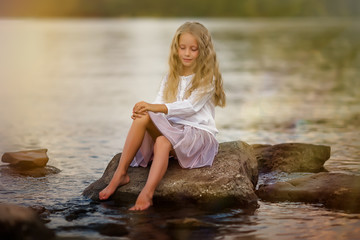 Portrait of a cute girl on the lake in the sunset on a summer evening.