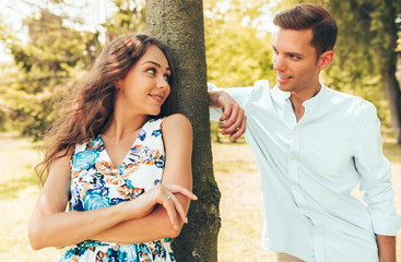 Obraz premium Young couple looking to each other with love. Portrait of man and woman posing outdoors in the park.