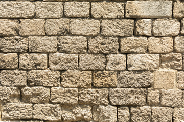 Masonry wall of old stone blocks of limestone. Background texture of ancient brick wall