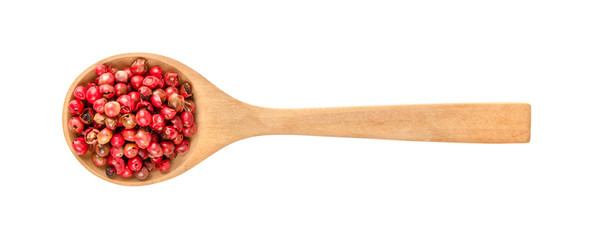 dried pink peppers in wood spoon isolated on white background