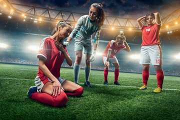 Obraz na płótnie Canvas Sad Female Soccer players on a professional soccer stadium. Girls Team crying