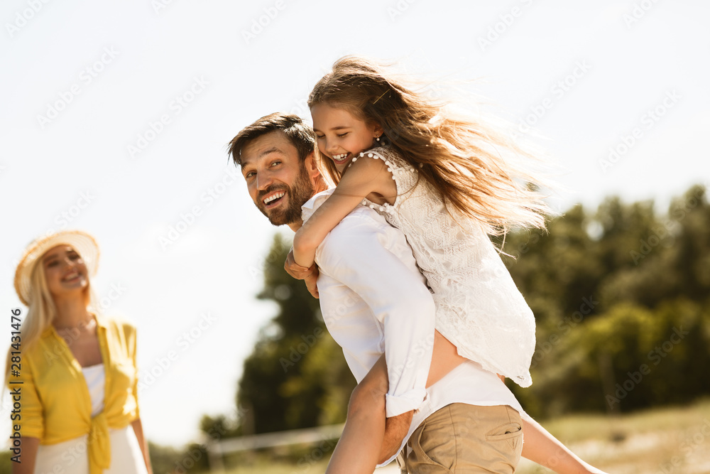 Wall mural happy father carrying his daughter on back outdoors