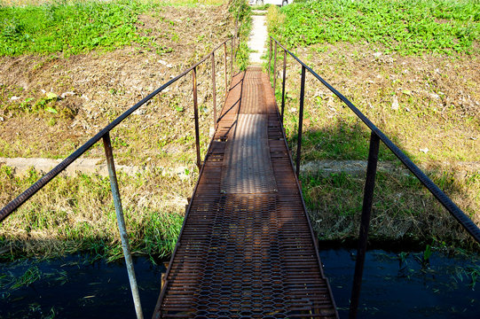 Old metal bridge over a small river.
