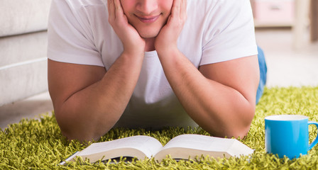Man reading book at home on floor