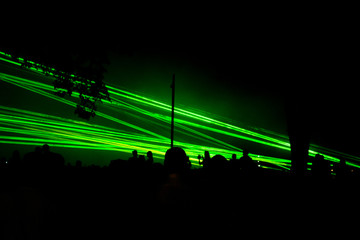 A colorful laser show in the club, on the street with a lot of party-goers