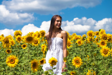 Fototapeta na wymiar Portrait of a young beautiful girl in a field of sunflowers