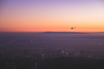 Mountain overlooking the city of Los Angeles with Helicopter during sunset