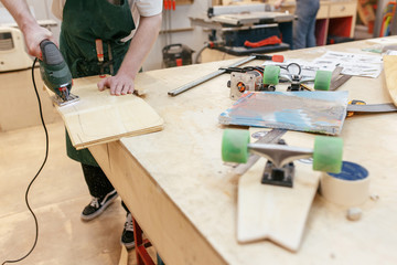 Unidentified male carpenter jigsaw out the base for a skateboard. Concept of a professional...