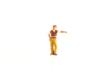 Miniature Person Pointing at Something Standing on a White Isolated Background