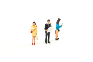 Obraz premium Miniature People Looking at Media/Newspaper/Phone Standing on a White Isolated Background
