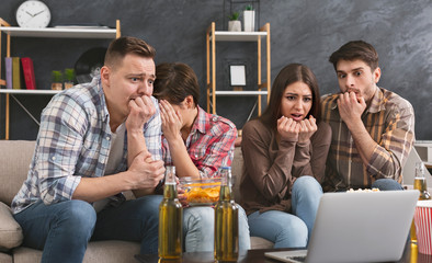 Shocked friends watching horror movie on laptop at home