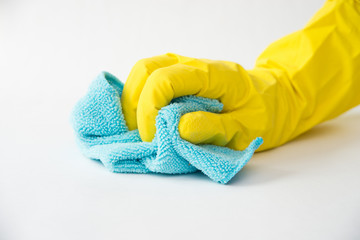 Closeup of a hand in a yellow latex glove using a blue towel to clean a counter top.