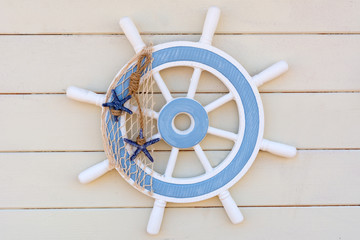 Blue wooden ship steering wheel as decoration on white wooden background