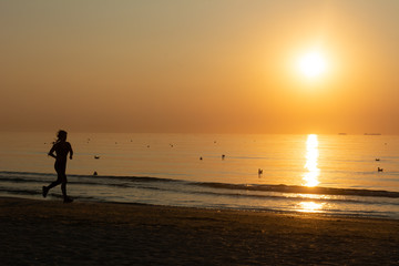 Fototapeta na wymiar Woman running on the beach at sunrise