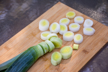 Organic fresh cutted leeks on the wooden cutting board. Leek cut by means rings on a chopping board. Slices of the fresh green leek. Cooking ingredients.