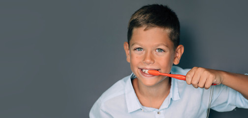 Cute boy brushing his teeth on gray background. Keeping teeth healthy and clean © Peakstock