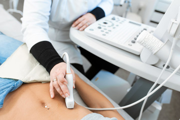 The doctor conducts an ultrasound of the stomach of a young girl. Close-up of equipment