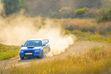 Obraz na płótnie Canvas Blue Rally Car Passes Turn of the Road