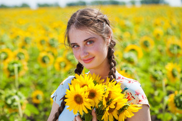 Portrait of a young beautiful girl in a field of sunflowers