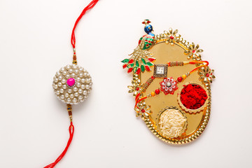Indian festival Raksha Bandhan , Rakhi with rice grains, kumkum and sweets on plate 