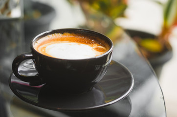 close up modern hot black coffee the cappuccino on dark background with coffee bubble foam pattern and texture in black cup looking and feel so delicious on glasses table in coffee shop.
